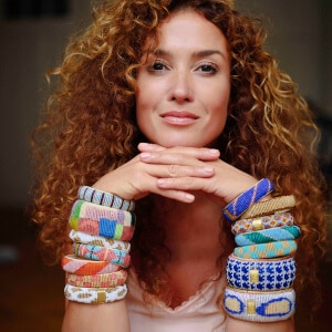 Fairer Schmuck - Rothaarige Frau mit Locken trägt viele bunte Armbänder