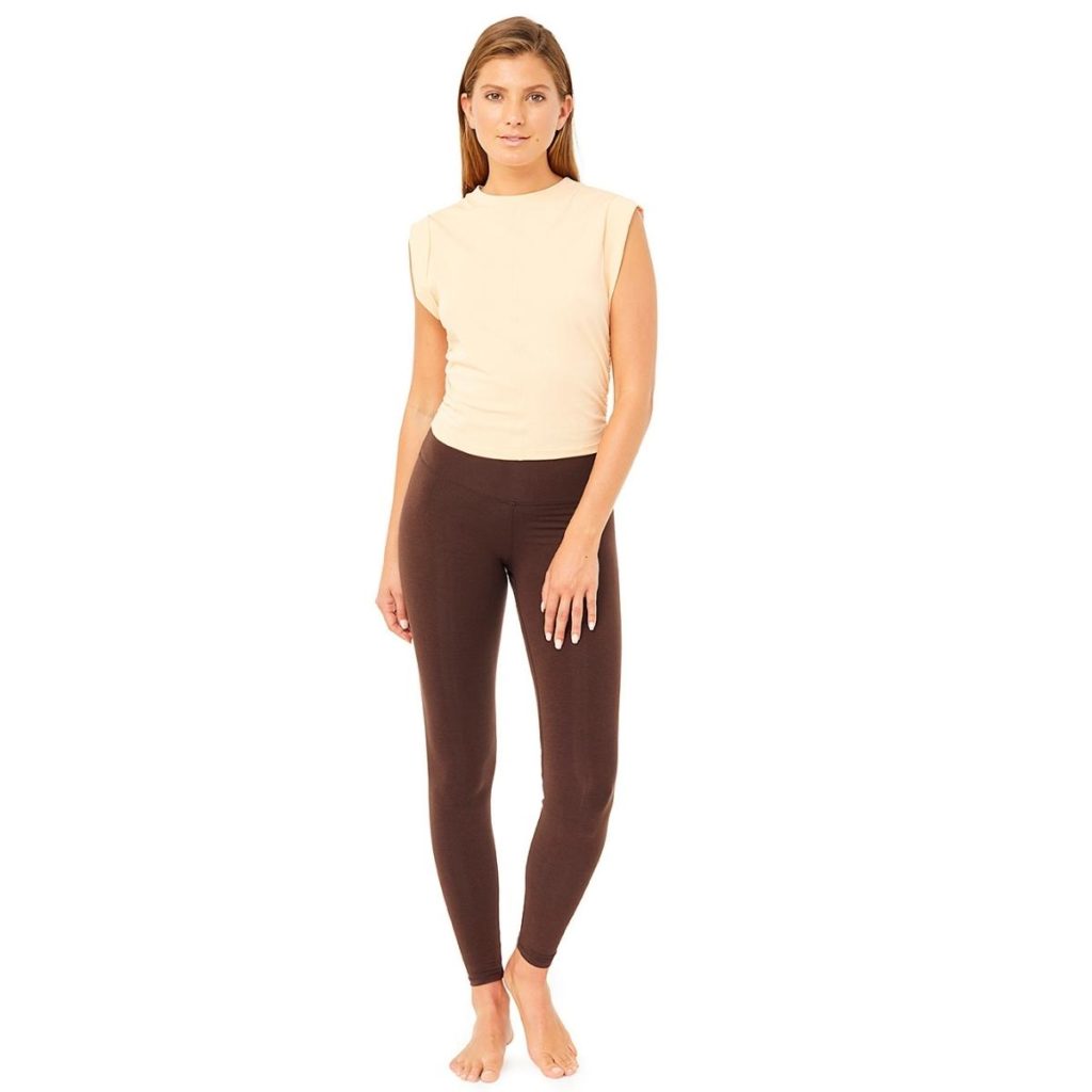 Frau trägt Yoga-Top in Mandarin und braune Yoga-Hose