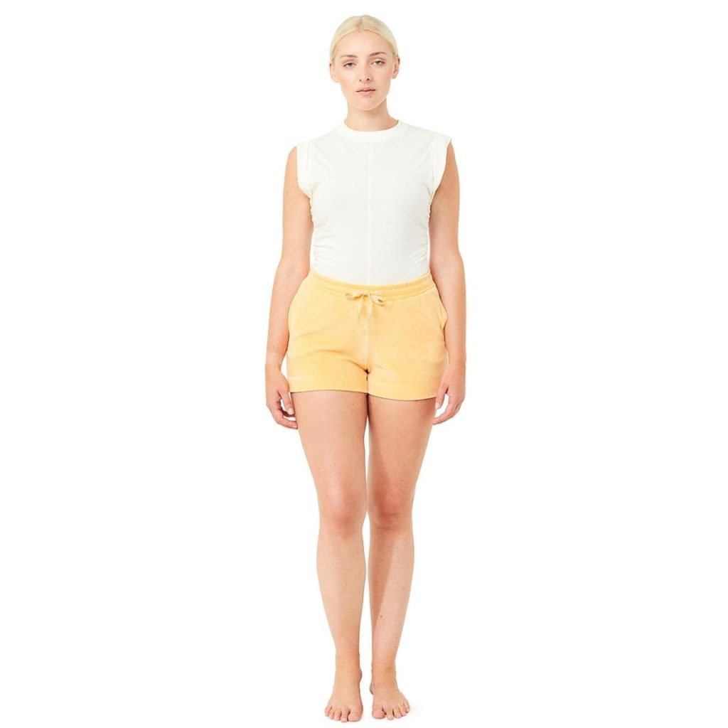 Frau trägt Yoga-Top in Weiß (Silk) und kurze Yoga Shorts