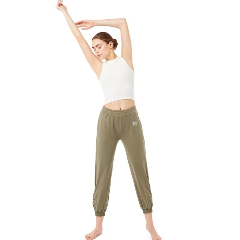 Frau macht Yoga im weißen Yoga Top und Olive-grüner Yoga Hose