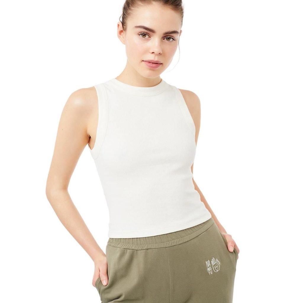 Frau trägt ein Yoga Top in Weiß und eine Olive-grüne Yoga Hose