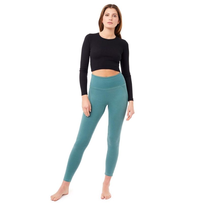 Frau trägt Yoga Legging in Türkis und ein schwarzes Yoga Langarmshirt