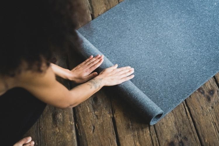 Mangolds Yoga-Online Shop - Frau rollt eine Yogamatte zusammen