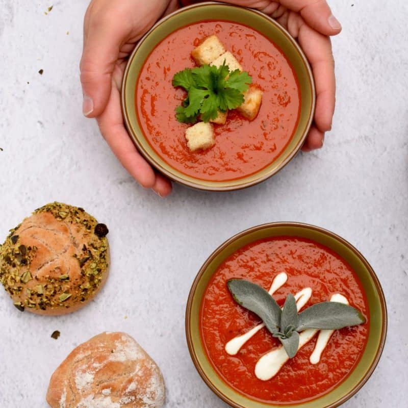 2 Suppenschüsseln mit Tomatensuppe und Gebäck